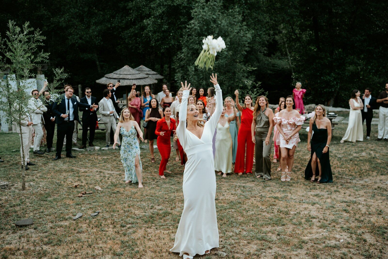 Bride throws bouquet to wedding guests outdoors
